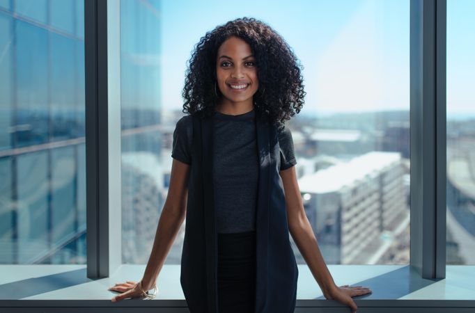 Portrait of woman with curly hair standing near window in office