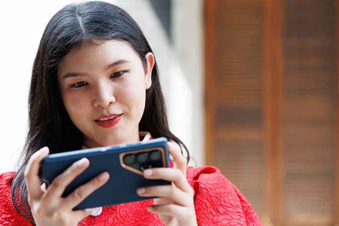 Asian woman in Chinese New Year shirt chatting on mobile phone