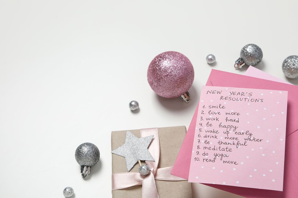 Gift boxes, balls and paper with list on light background, space for text