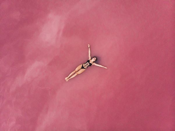 Carefree woman on vacation delighting in pink water of lake