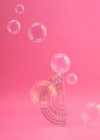 Protractor on pink background with bubbles