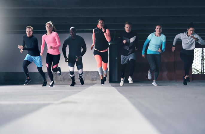 Group of people sprinting towards camera on concrete track