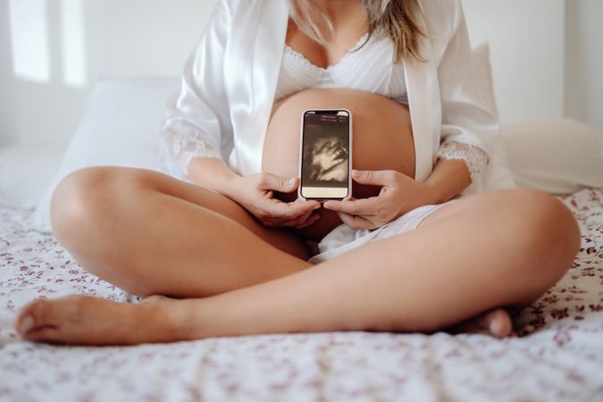 Faceless pregnant woman showing picture from ultrasound scan