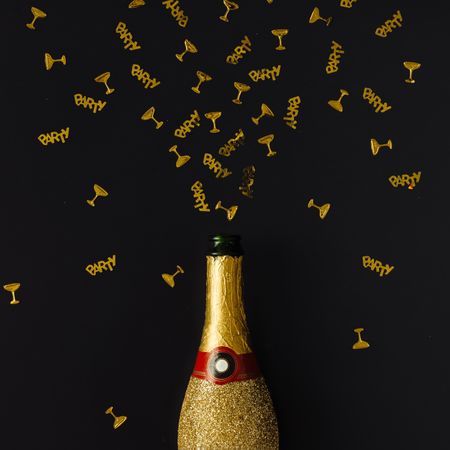 Golden champagne party bottle on background with gold confetti