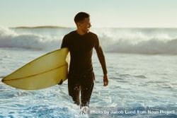 Smiling young man with surfboard on beach bD2YV5