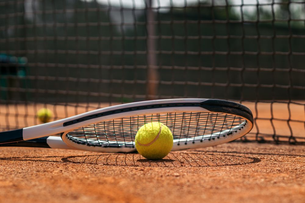 Tennis racket and ball on a dirt court