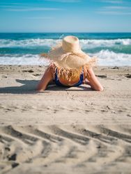 Woman in blue swimsuit and hat on sandy beach