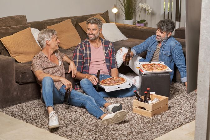 Cheerful friends having pizza and beer at home