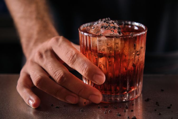 Anonymous bartender serving Negroni cocktail on counter