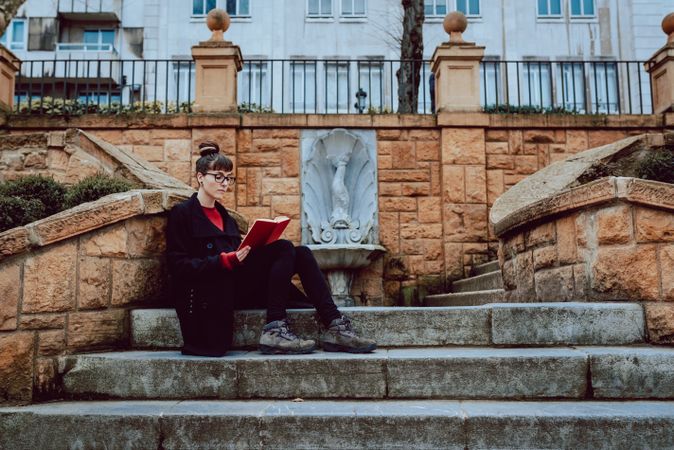 Young woman reading book on steps