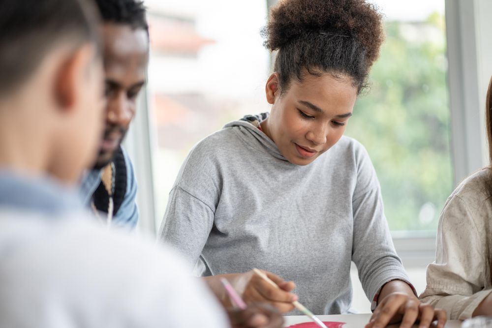 Black teenage student in painting class with teacher