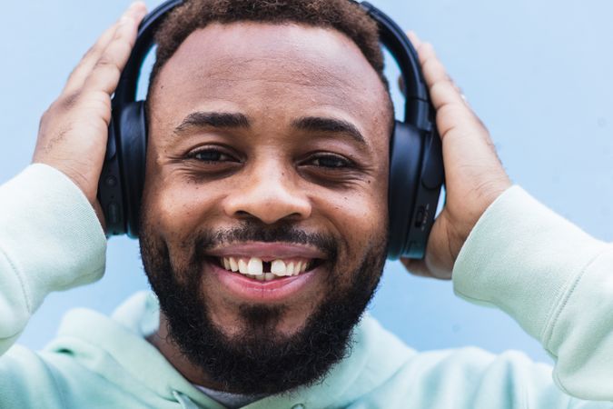 Optimistic Black hipster listening to music with headphones