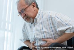 Older male with his hand holding his stomach in pain 5rjJZ5