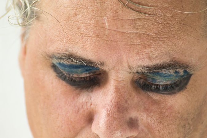 Close-up shot of sad middle aged man's closed eyes with dark eyeshadow