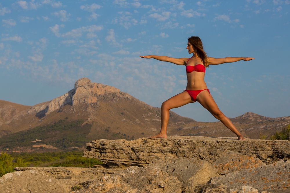 Woman in bikini posing on stone near mountains