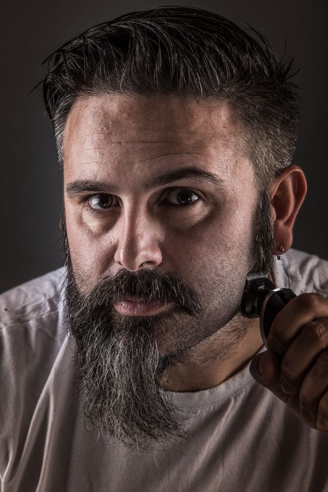 Barber shaving beard and looking at camera