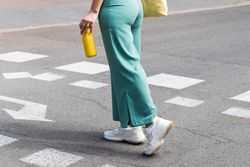 Crop woman crossing road in city