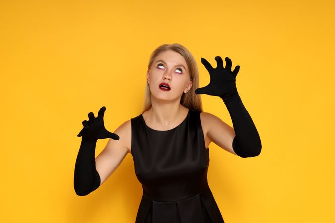 Concept of Halloween, young woman on yellow background