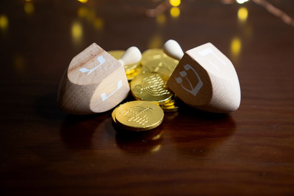 Two dreidels with gelt on wooden surface