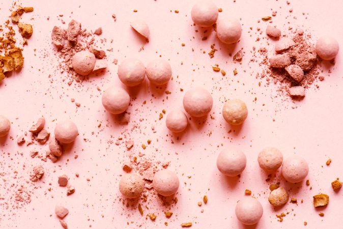 Powdered balls of eyeshadow and blush on pink background