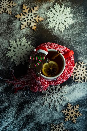 Top view of cup of mulled tea wrapped in cosy scarf with gingerbread cookie