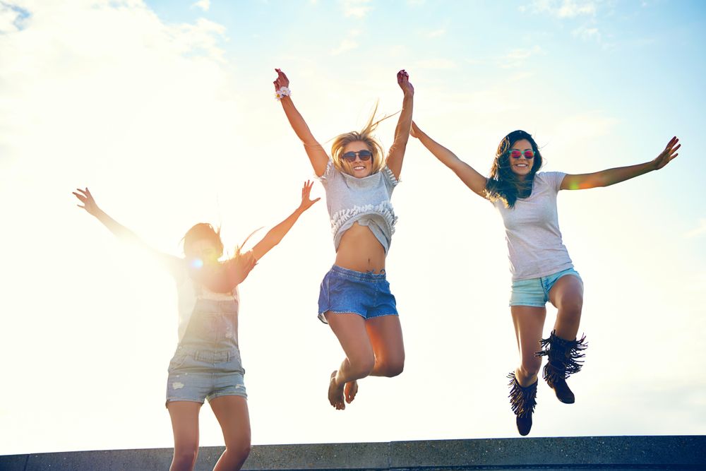 Happy female friends jumping for joy on sunny day