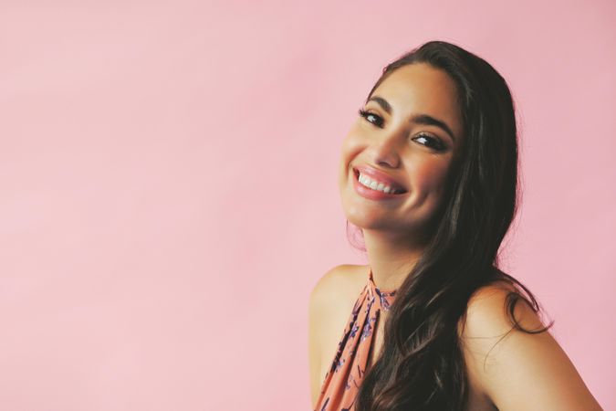Smiling Hispanic woman with head tilted back pictured in pink room