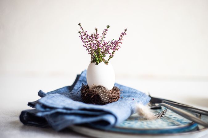 Easter table setting with side view of heather in decorative egg on blue napkin