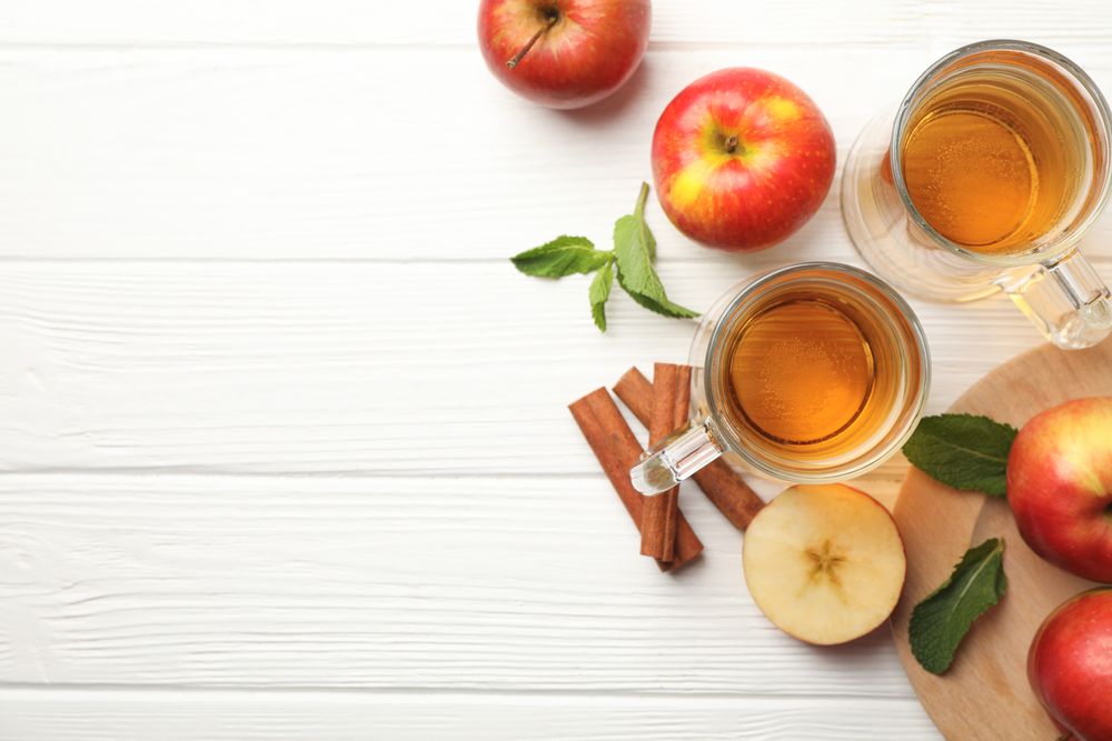 Composition with cider, cinnamon and apples on wooden background