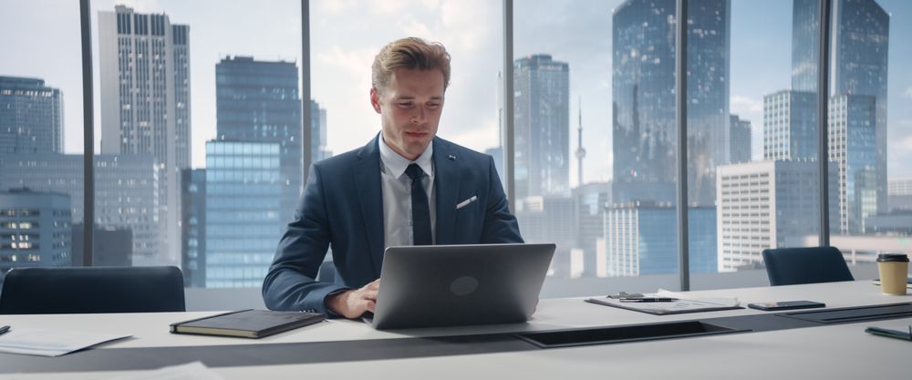 Confident Businessman in a Suit Sitting at a Desk in Office