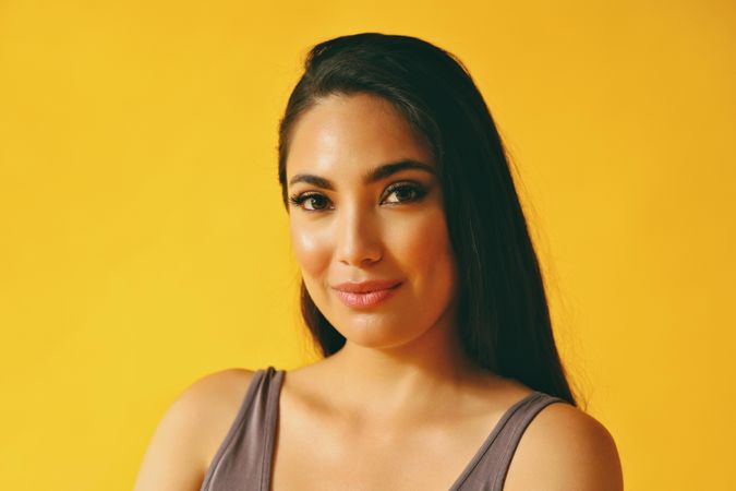 Calm smiling Hispanic woman looking at camera in yellow room