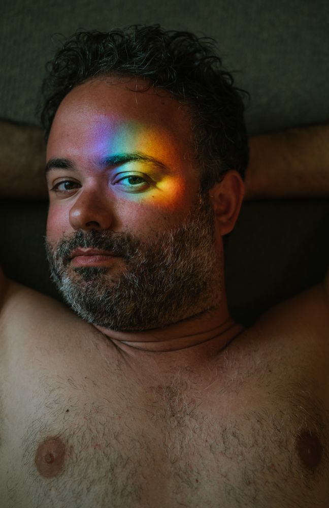 Bearded man with rainbow glare on face