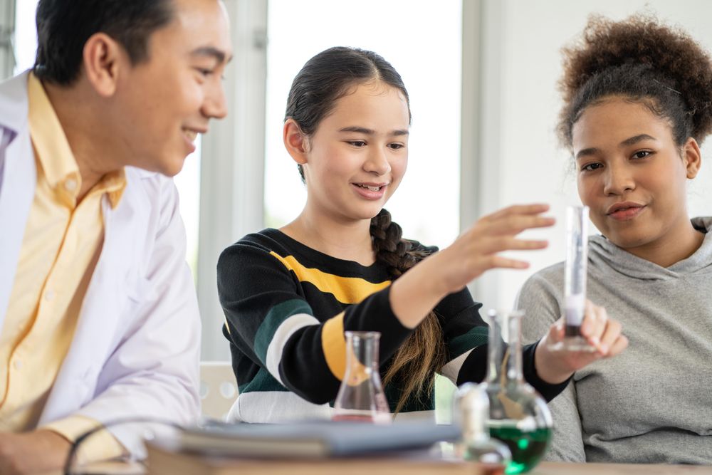 Students in science class doing chemical experiment with teacher