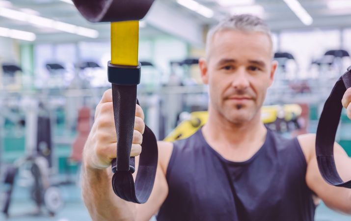 Man standing with suspension ropes in gym