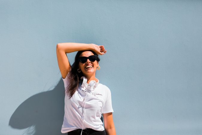 Cheerful casual woman in sunglasses standing on city street