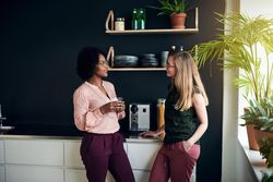 Two female colleagues discussing work in the break room