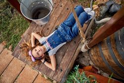 Dreamy girl on wooden platform in rural yard