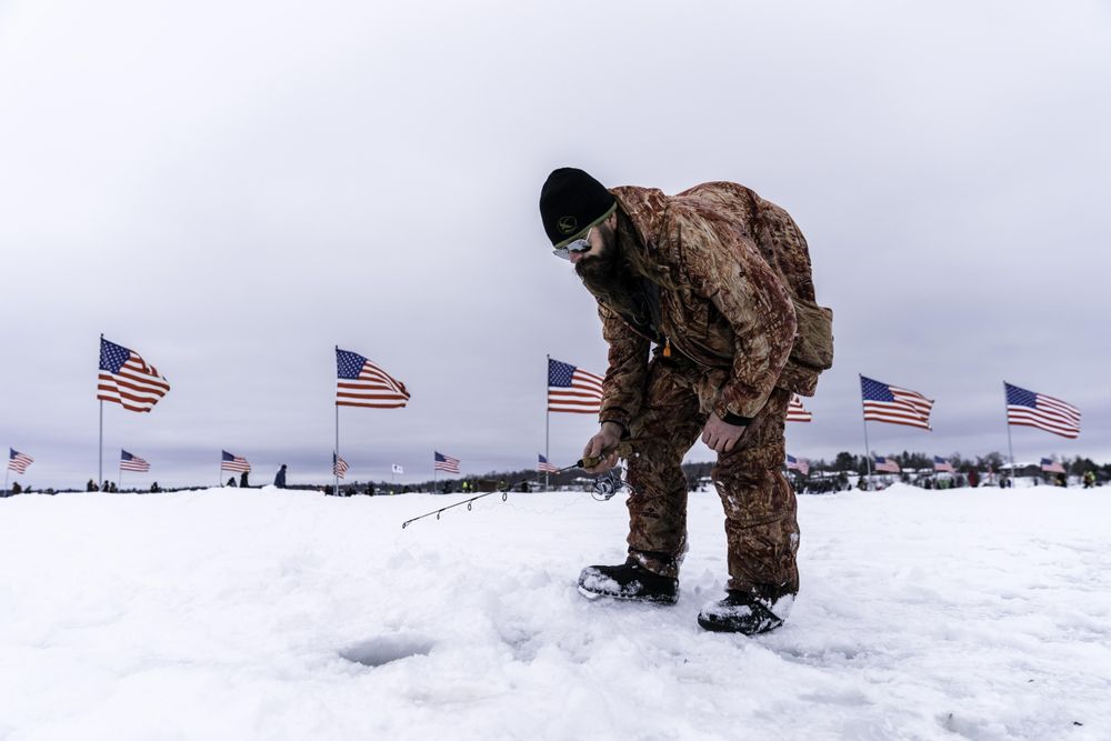 Nisswa, MN, USA - January 25th, 2020: A man ice fishing dressed in camouflage