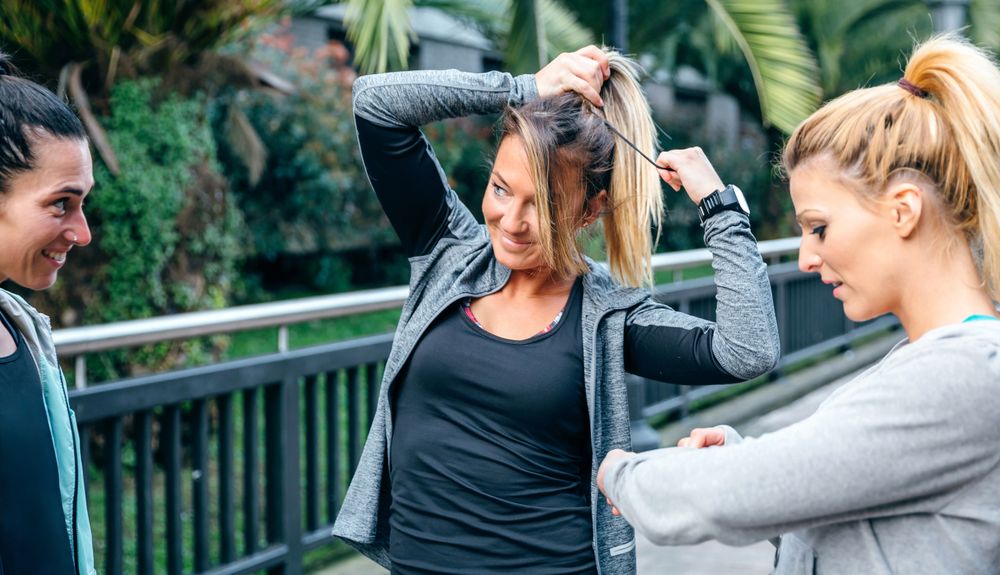 Blonde female runner tying her hair in a ponytail before training