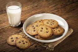 Delicious chocolate cookies with glass of milk on wooden table.
