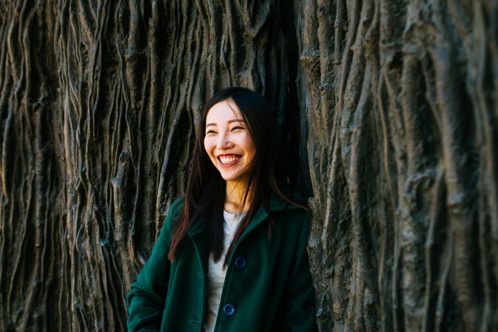 Cheerful Asian woman leaning on rough wall