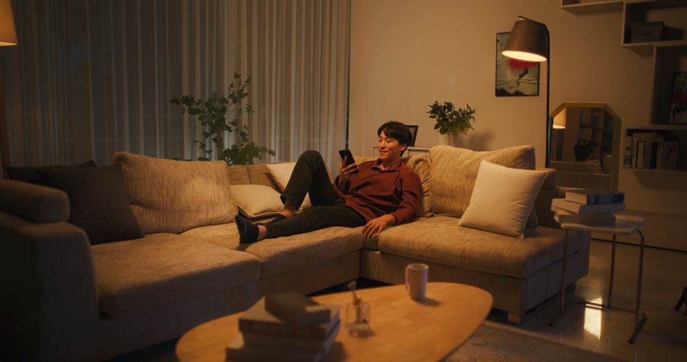South Korean Young Man Enjoying His Leisure Time while Relaxing and Using a Smartphone.