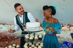 Bride and groom laughing behind wedding cake