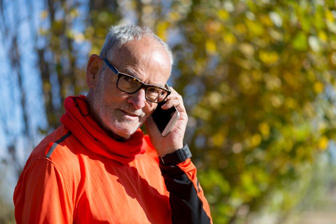 Portrait of older male talking on phone in park