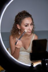 Focused female visagiste shading blush with brush on cheek