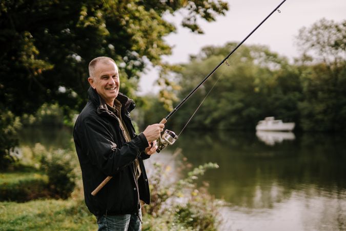 Smiling man sitting and fishing by river