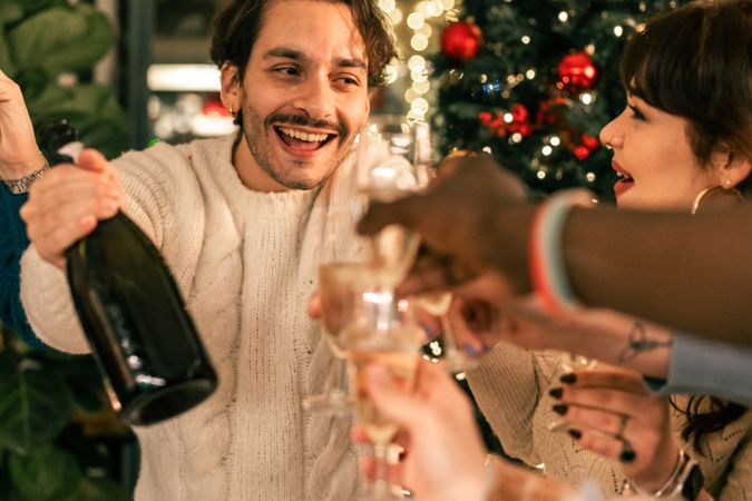 Joyful man laughing and toasting with friends at a Christmas party.