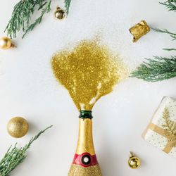 Christmas layout made of Champagne popped with gold glitter pouring out on light background