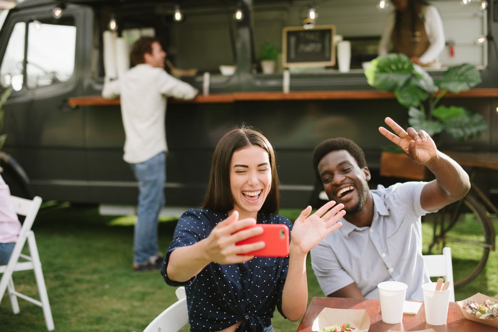 Diverse friends talking selfie near food truck