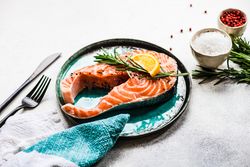 Salmon fish with rosemary and lemon on stone background with copy space